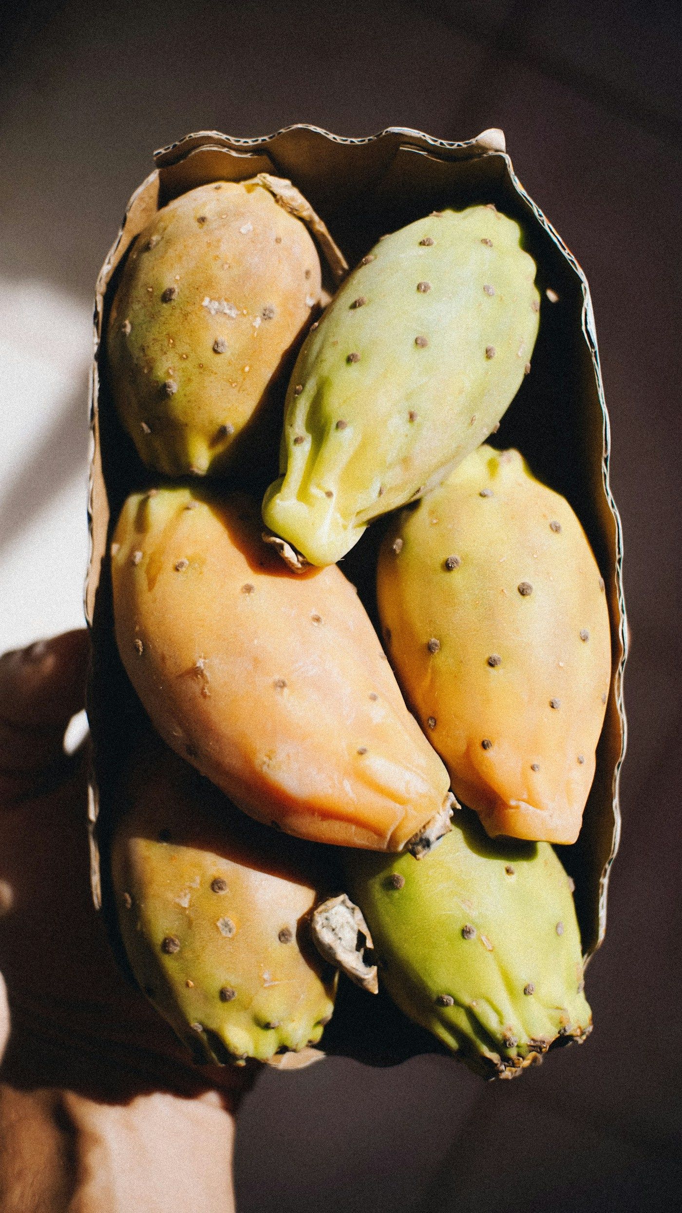 Figues de Barbarie épluchées, tenues dans un papier kraft.